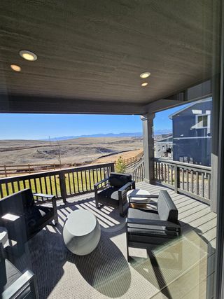 Community Amenities A modern patio with sleek black furniture, round tables, and stunning views of open fields and mountains.