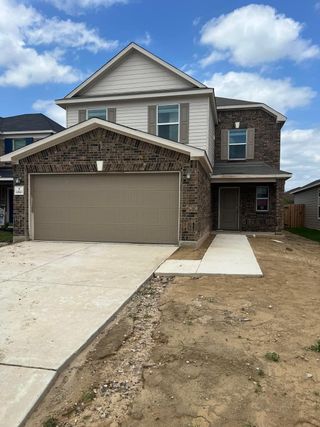 A beautiful home with traditional brick accents and a spacious driveway in the Preserve at Culebra by KB Home (San Antonio, TX).