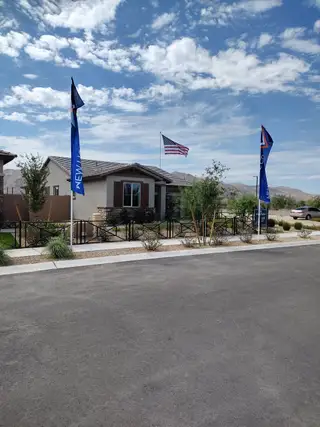 A modern home with a tiled roof and flags in The Residences Collection at Frontera by New Home Co. (Surprise, AZ).