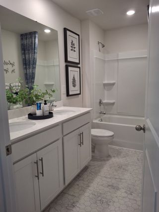 A modern bathroom featuring dual sinks, hexagon tile flooring, and elegant floral decor with soft lighting accents.
