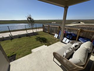 Model Home A cozy patio overlooks a serene lake and landscaped yard in Waterstone: Stonehill Collection by Lennar (Kyle, TX).