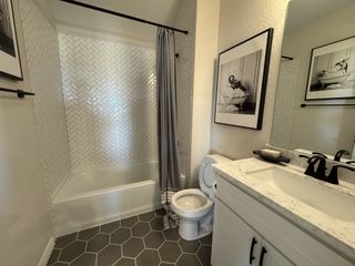 A beautifully designed bathroom with a white vanity, black hardware, and a herringbone-patterned shower wall.