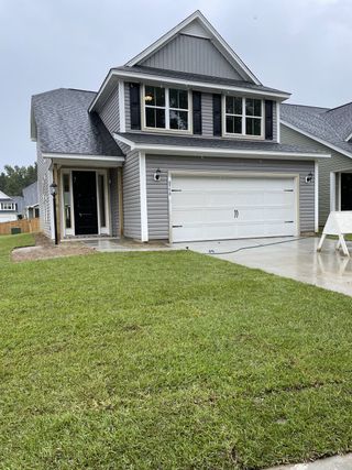 A modern gray home with a neat lawn and two-car garage in Windsor Crossing by Dream Finders Homes (North Charleston, SC).