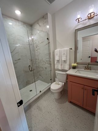 A chic bathroom with a glass-enclosed shower, coral vanity, and elegant lighting. Modern fixtures add a touch of luxury.
