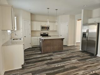 Bright kitchen with white cabinetry, stainless appliances, a center island, and dark wood flooring.