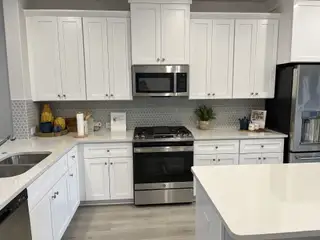 A modern kitchen featuring white cabinetry, sleek stainless appliances, and a chic hexagonal tile backsplash.