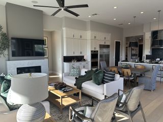 Model Home An open-concept living space with a modern fireplace, plush seating, and a seamless transition to the elegant kitchen and dining area.