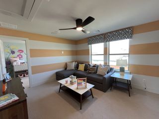A fun and inviting game room with bold striped walls, cozy seating, and ample natural light in Solterra by David Weekley Homes (Mesquite, TX).