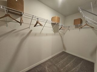 A spacious walk-in closet with wire shelving, carpeted floors, and storage bins for organized living.