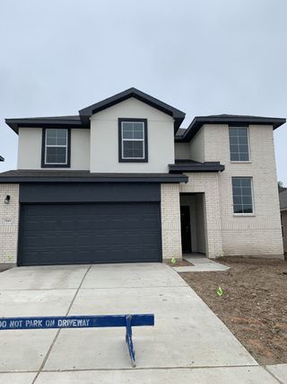 A contemporary home with a dark garage and white brick exterior in Bar W Ranch by D.R. Horton (Leander, TX).