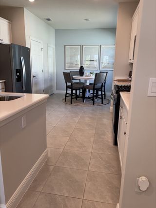 A modern kitchen dining area with tiled floors, sleek appliances, and a stylish round table set.