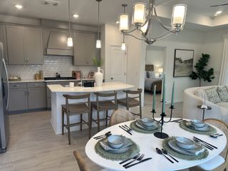 A modern kitchen and dining area with gray cabinets, an island, and elegant tableware, offering a cozy and stylish ambiance.