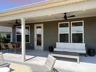 A spacious covered patio with sleek outdoor seating, a modern ceiling fan, and a dining set for relaxed gatherings.