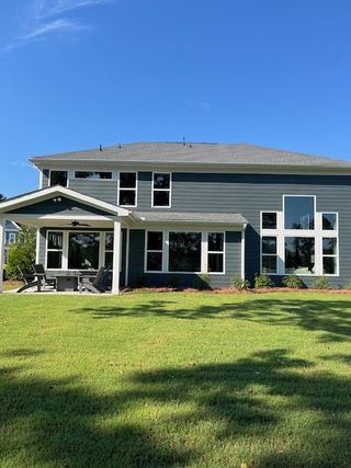 Street view A modern gray home with expansive windows and a lush lawn in Sweetbay Farm by Fischer Homes (Lawrenceville, GA).