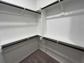Spacious walk-in closet with white shelving and sleek black rods for organized storage.