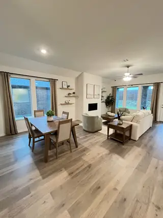 Model Home An inviting open living space with wood floors, a cozy dining area, and a bright, modern seating arrangement.