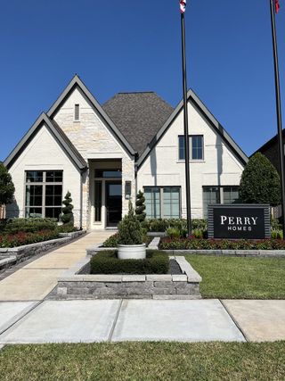Street view A beautiful white brick home with a manicured garden in Sienna 55' - Valencia by Perry Homes (Missouri City, TX).