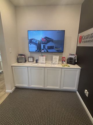 A modern sales office with a sleek TV display, informational brochures, and minimalistic cabinetry.