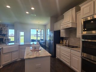 A spacious kitchen with white cabinetry, granite countertops, and stainless steel appliances, leading to a bright dining area.