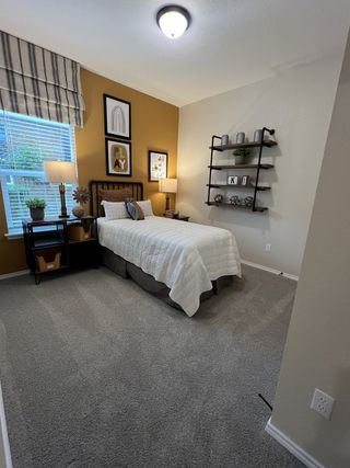 A bright office featuring a wooden desk, two black chairs, a patterned rug, and a unique highland cow artwork, creating a stylish workspace.