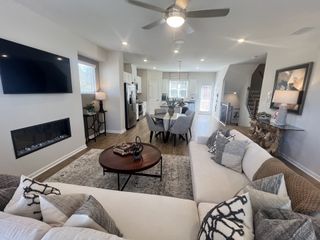 Model Home An open-concept living area with a modern fireplace, large sectional sofa, and a bright, airy kitchen.