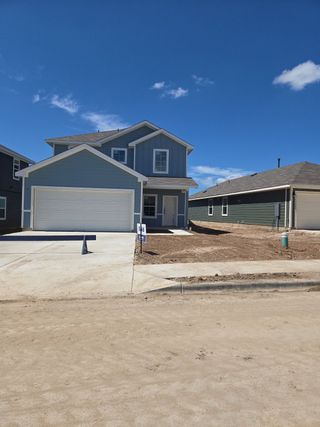 Street view A modern blue home with a two-car garage in Durango by D.R. Horton (Mustang Ridge, TX).