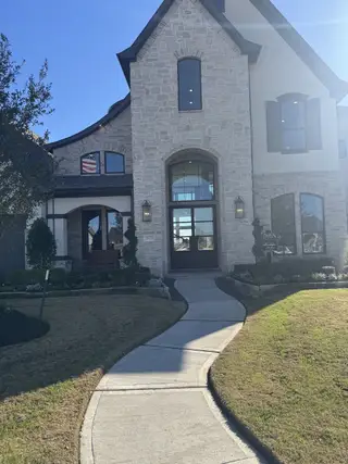 A stunning stone facade home with elegant windows and manicured landscaping in Dunham Pointe 70' by Newmark Homes (Cypress, TX).