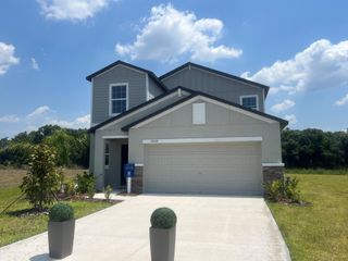 A modern two-story home with a neat driveway and landscaped yard in Prosperity Lakes by Lennar (Parrish, FL).
