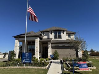 A modern stone and stucco home with manicured landscaping in 6 Creeks by New Home Co. (Kyle, TX).