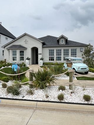 Street view Charming white brick home with lush landscaping in Venetian by Megatel Homes (Celina, TX).