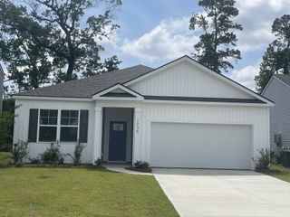 A charming white paneled home with a spacious garage and lush greenery in Pineview North by D.R. Horton (Summerville, SC).