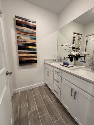Model Home A sleek bathroom with wood-style tile flooring, modern white vanity, and stylish wall art for a contemporary look.