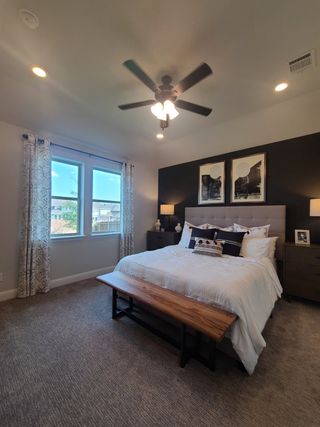 A cozy bedroom featuring a tufted bed, stylish artwork, and a wooden bench, complemented by soft lighting and carpeted floors.