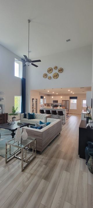 A spacious living area with high ceilings, modern décor, and an open kitchen, featuring elegant lighting and wood flooring.