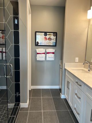 A modern bathroom with hexagonal tile shower, sleek vanity, and artistic decor.