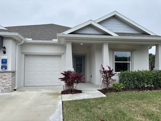 A charming modern home with a neat porch and lush landscaping in Lakes At St Sebastian by Holiday Builders (Micco, FL).
