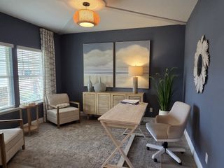 A sophisticated home office with navy accent walls, natural wood furniture, and modern lighting offers a serene workspace.