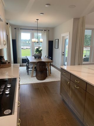 A modern kitchen-dining area with sleek cabinetry, hardwood floors, and a view of the lush outdoors.