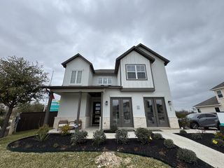 Modern two-story home with a white exterior, dark accents, and a landscaped front yard under a cloudy sky.