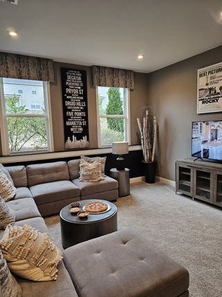 A modern game room with large windows, a sectional sofa, and elegant wall art, offering a perfect space for hosting guests.