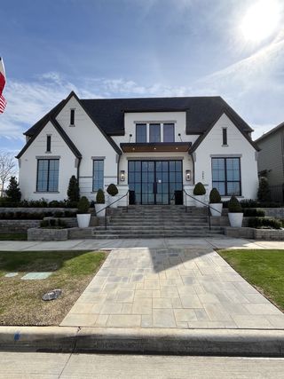 A grand white home with sleek lines and manicured landscaping in Fields by Huntington Homes (Frisco, TX).