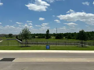 Street view Scenic open space with lush greenery and a fenced area in Homestead Village by Meritage Homes (Round Rock, TX).