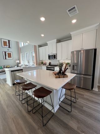 Model Home A contemporary kitchen with white cabinetry, a spacious island, and stainless steel appliances in Solterra by Chesmar Homes (Mesquite, TX).