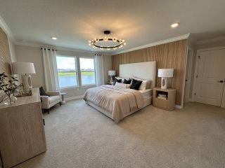 A serene bedroom with textured walls, chic lighting, plush bedding, and lake views.