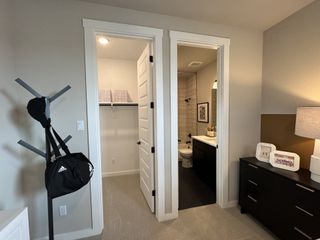 A cozy room featuring a sleek dresser, modern coat rack, and an ensuite with a tile-accented bathroom and walk-in closet.