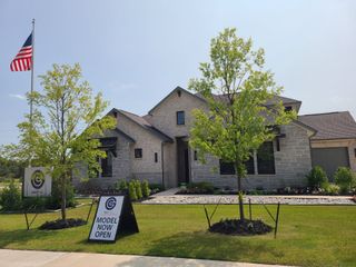 Street view A beautiful stone home with lush landscaping in Oaks Preserve by GFO Home, Mansfield, TX.