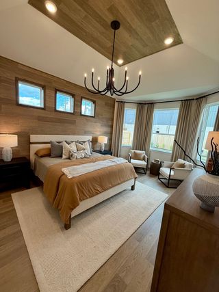 A cozy bedroom with wood accents, elegant chandelier, and large windows. Warm tones create a welcoming ambiance.