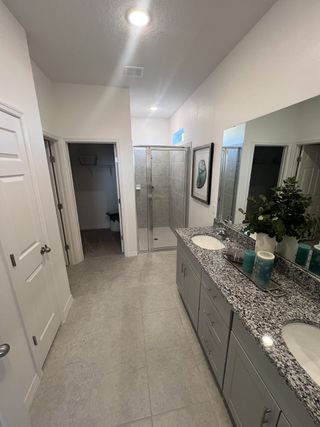 A spacious bathroom featuring a sleek double vanity, granite countertops, and a glass-enclosed walk-in shower.


