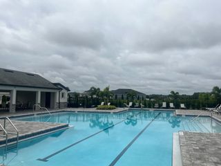 Community Amenities An inviting community pool with lounge chairs and a clubhouse at Geneva Landings by Highland Homes of Florida (Davenport, FL).