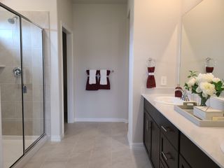 A sleek bathroom featuring a glass shower, dark vanity, and elegant decor with fresh flowers.